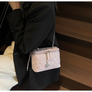 Close-up of pink quilted crossbody bag with sparkling rhinestones and rose pendant detail