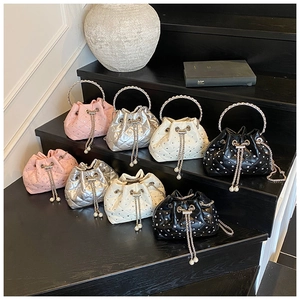 Close-up of quilted bucket bags in four colors with pearl drawstring chains and metal handles
