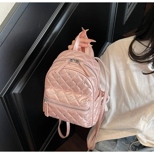 Close-up of pink quilted backpack with sparkling rhinestone details and gold zipper