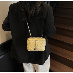 Close-up of yellow quilted chain bag with crystal studs and camellia flower charm