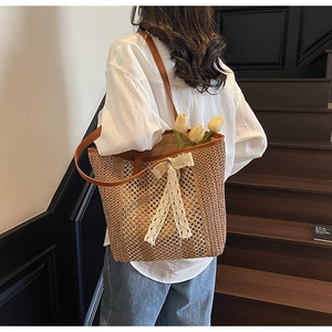Détail du sac cabas en paille tressée avec grand nœud en dentelle blanche et anses en cuir