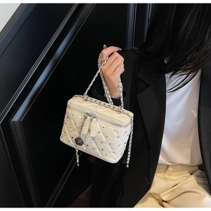 Detail of cream quilted crossbody bag with rhinestone studs and silver rose pendant
