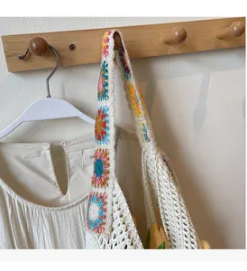 Detail of bohemian knit tote bag featuring colorful crochet floral shoulder straps