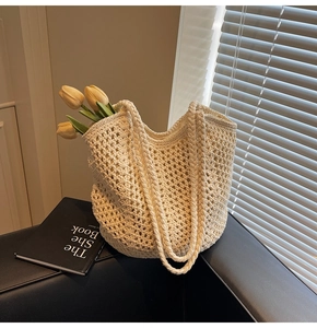 Detail of beige woven tote bag with intricate mesh pattern and sturdy dual handles