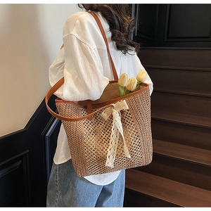Détail du sac fourre-tout en paille tissée avec grand nœud en dentelle blanche
