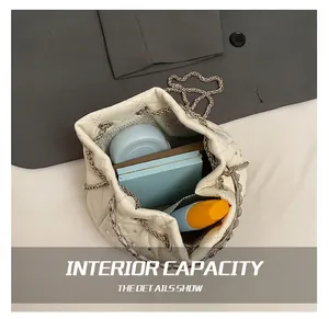 Interior view showing capacity of the white quilted bucket bag with chain drawstring