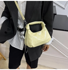 Détail du sac à main en cuir verni jaune clair avec breloque papillon argentée et poignée