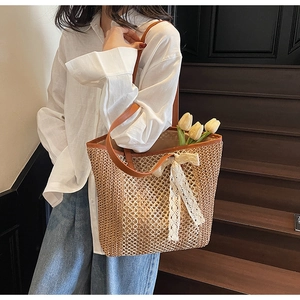 Détail d'un sac cabas en paille tissée avec nœud en dentelle et anses en cuir brun