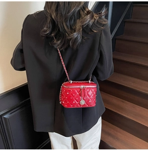 Close-up of red quilted crossbody bag with diamond studs and metal chain strap