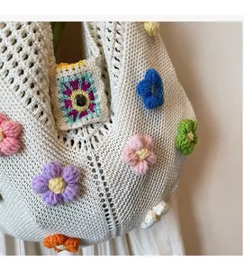Close-up of white crochet handbag featuring colorful 3D knitted floral decorations