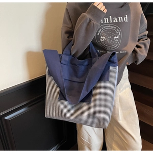 Detail of a large denim tote bag featuring navy canvas and black-white checkered stitching