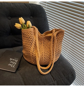 Close-up of a hollow woven tote bag featuring thick braided straps and straw texture