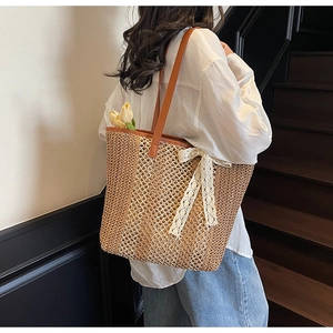 Détail du sac cabas tressé avec bandoulière en cuir marron et nœud décoratif en dentelle