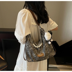Detail of floral tote bag with removable pearl chain and white plush cloud charm