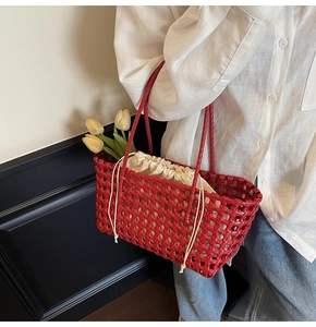 Gedetailleerd zijaanzicht van een rode gevlochten tote bag met beige binnentas bij een model