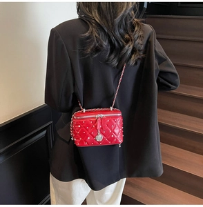 Close-up of red quilted leather box bag with silver studs and camellia pendant detail