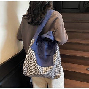 Detail of a large canvas tote bag with contrast gingham pattern and double handles