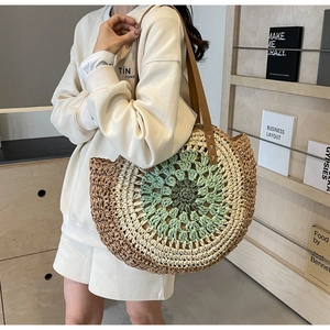 Detail of bohemian round straw bag with colorful floral weaving and brown leather strap
