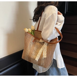 Détail d'un sac cabas en paille tissée avec ruban en dentelle blanche et anse en cuir