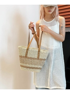Large woven tote bag with brown leather straps shown on a model in a white knit dress