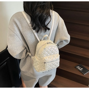 Detailed shot of a beige mini quilted backpack with sparkling rhinestones and silver zippers