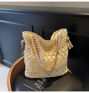 Dettaglio ravvicinato di una borsa tote in paglia intrecciata con tracolla etnica colorata su sedia