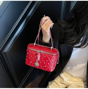 Detail of red quilted mini box bag with silver studs and a rose metal charm