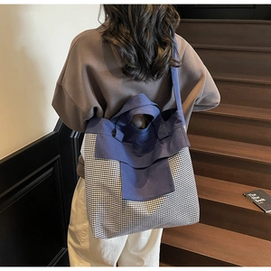 Detail of vintage denim tote bag showing plaid patchwork and thick canvas texture on model