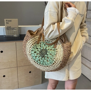 Close-up of hollow out woven straw tote bag with green accents and leather straps