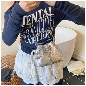 Detailed macro view of silver quilted bucket bag featuring rhinestone accents and metal handle