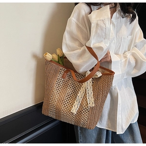 Détail d'un sac cabas tissé avec poignées en similicuir marron et nœud en dentelle blanche