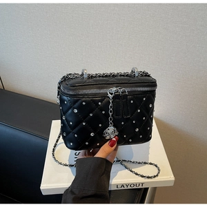 Close-up of black quilted mini bag featuring sparkling rhinestones and rose zipper puller