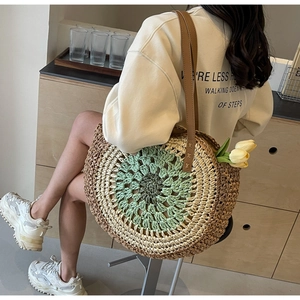 Detail of bohemian round straw bag featuring gradient spiral weave and brown leather strap