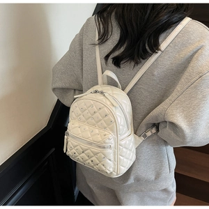 Close-up of white quilted mini backpack with rhinestone decor on a female model
