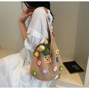 Detail of knit tote bag featuring colorful 3D crochet flowers and wide woven strap