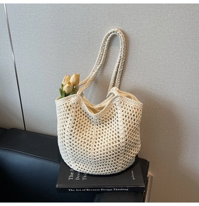 Detail of hollow woven beige tote bag with yellow tulips on a minimalist book background