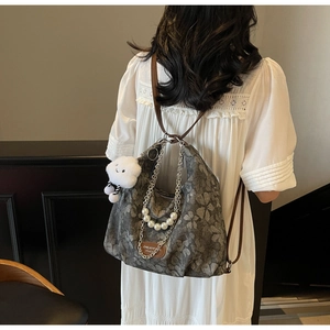 Detail of floral crossbody bag with pearl chain, metal strap and plush cloud charm