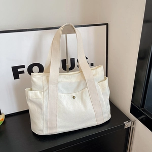 Detail shot of cream canvas tote bag with functional pockets and vintage metal buckle