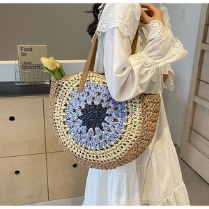 Detail of a large mandala crochet straw tote bag with brown leather shoulder straps