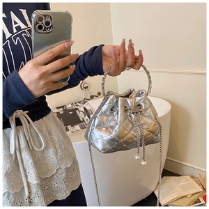 Close-up of silver quilted bucket bag with metal ring handle and pearl drawstring charms