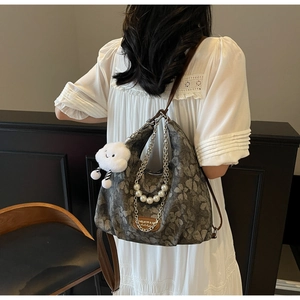 Detail of vintage floral tote bag with pearl chain and white cloud plush charm