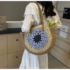 Detail of crochet floral pattern and handwoven texture on a round straw beach tote bag