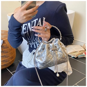 Detail of silver quilted bucket bag with rhinestones, metal ring handle and pearl charm