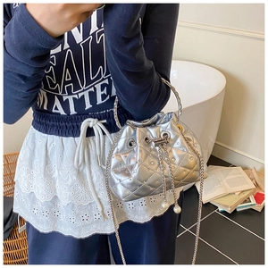 Close-up of silver quilted bucket bag with rhinestone studs and metallic chain strap