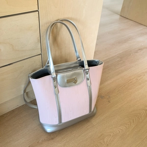 Detail view of pink textured tote bag with silver handles and heart pendant decoration