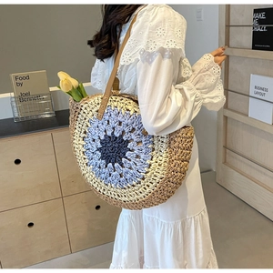 Detail of round straw tote bag with colorful radial weave pattern and leather strap