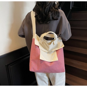 Detail of red and white gingham canvas tote bag with reinforced handles and shoulder straps