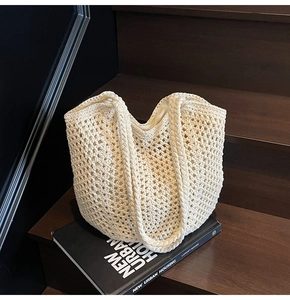 Detailed close-up of cream woven tote bag with hollow mesh design on a brown staircase
