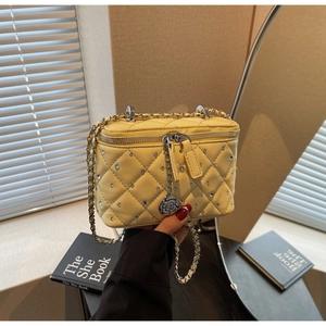 Detail of yellow quilted box bag with sparkling rhinestones and floral charm pullers