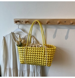 Detail van gele geweven shopper met trekkoord voering hangend aan een houten haak